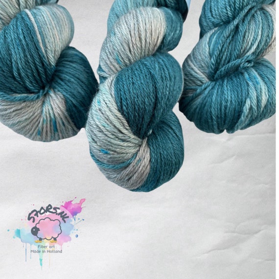 Hand dyed superwash Merino and bamboo DK weight yarn. Pooling teal green with grey and blue speckles.