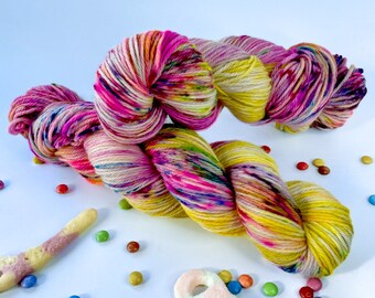 Handgeverfd superwash merino, kasjmier en nylon DK-gewichtsgaren. Marshmellow roze en geel met fluorescerende spikkels.