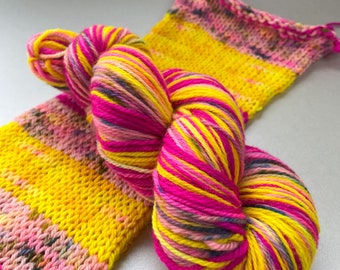 Self striping hand dyed superwash Merino DK weight yarn. Fluoriscent pink with yellow and speckled light pink.