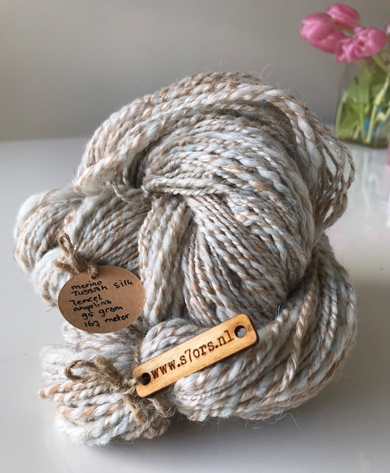Hand spun merino wool, tussah silk and angelina sparkle blend yarn. Sport weight. In natural beige with some sparkly rainbow colours.
