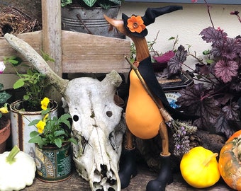 Wilma die Hexe Holzente mit Stiefeln. Orangefarbene Hexe mit Hexenhut und Hexenzauberumhang, Besenstiel und einem Strich oder Magie.