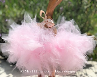 Powder pink tutu wearing, wooden duck, with rose gold boots and matching pink ribbon.