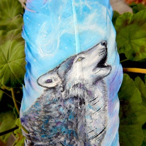 Puede incluir: Una pluma pintada con un lobo aullando a la luna. La pluma est&aacute; pintada en tonos de azul, morado y blanco. El lobo est&aacute; pintado en tonos de gris y blanco.