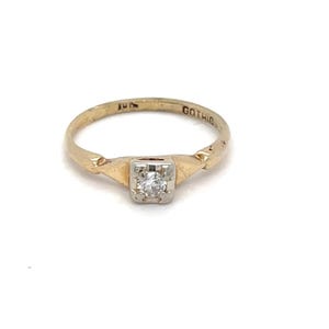 May include: A gold ring featuring a single round clear stone set in a square white metal head. The band is yellow gold and includes the engraved text GOTHIC on the inner surface. The design showcases a contrast between the gold band and the stone.