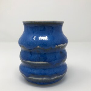 May include: A blue ceramic vase with a wavy design. The vase has a glossy finish and is decorated with white streaks.