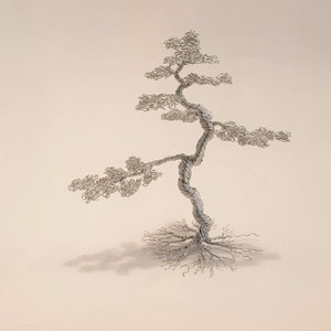 May include: A handcrafted silver wire sculpture of a bonsai tree. The tree features a twisted trunk, delicate branches, and a detailed root system. The sculpture is set against a neutral background, highlighting the intricate details of the wire art.