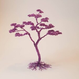 May include: A handcrafted, decorative wire tree sculpture in a vibrant purple hue. The tree features a twisted trunk, delicate branches, and a full crown of leaves, with intricate root details at the base. This unique piece is a decorative accent.