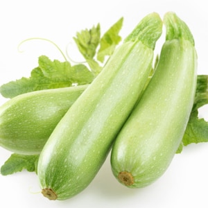 Könnte beinhalten: Drei grüne Zucchini mit Blättern auf weißem Hintergrund.