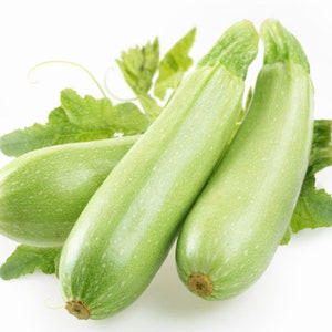 Könnte beinhalten: Drei grüne Zucchini mit Blättern auf weißem Hintergrund.