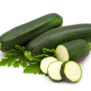 Könnte beinhalten: Drei grüne Zucchini, zwei ganz und eine in vier Scheiben geschnitten, mit einem grünen Blatt.