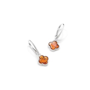 Peut inclure: Une paire de boucles d'oreilles pendantes en argent. Chaque boucle d'oreille présente un motif de trèfle à quatre feuilles avec un centre ambré chaud et une bordure perlée argentée. Sur fond blanc.