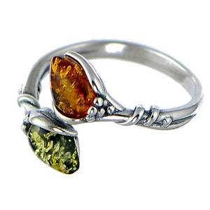 Peut inclure: Une bague en argent avec deux pierres d'ambre. Les pierres sont serties dans un motif en forme de feuille. La bague est torsadée et présente un motif floral délicat.
