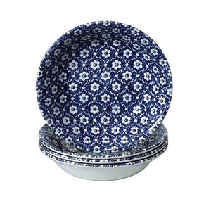 May include: A stack of four white ceramic bowls with a blue floral pattern. The bowls have a rounded shape and a wide rim. The floral pattern is a repeating design of small white flowers on a dark blue background.