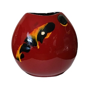May include: A round, red ceramic vase with a glossy finish. The vase features abstract black, yellow, and orange painted designs. The rim is black. A decorative piece for home decor.