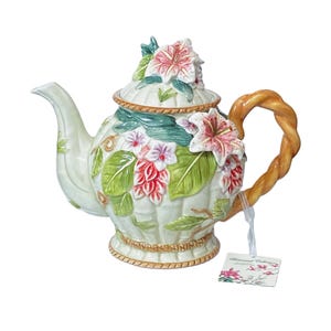 May include: A decorative ceramic teapot with a woven handle and floral accents. The teapot is primarily white with green, pink, and red floral designs. The handle is a twisted brown color. The teapot has a lid with more floral accents.