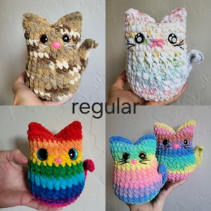 May include: Four crocheted cat toys in different colors and patterns. The first cat is brown and tan with a pink nose. The second cat is white with a rainbow pattern. The third cat is rainbow colored. The fourth cat is pink and blue with a rainbow pattern.