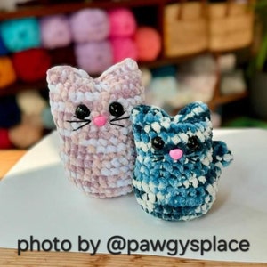 May include: Two crocheted cat toys, one pink and white and one blue and white. The toys have black eyes and pink noses.