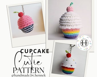 May include: Three crocheted cupcake keychains with a rainbow, pink and white frosting. The cupcakes have a cherry on top and are attached to a silver chain. The image includes the text "CUPCAKE Cutie PATTERN @handmade.by.hennek".