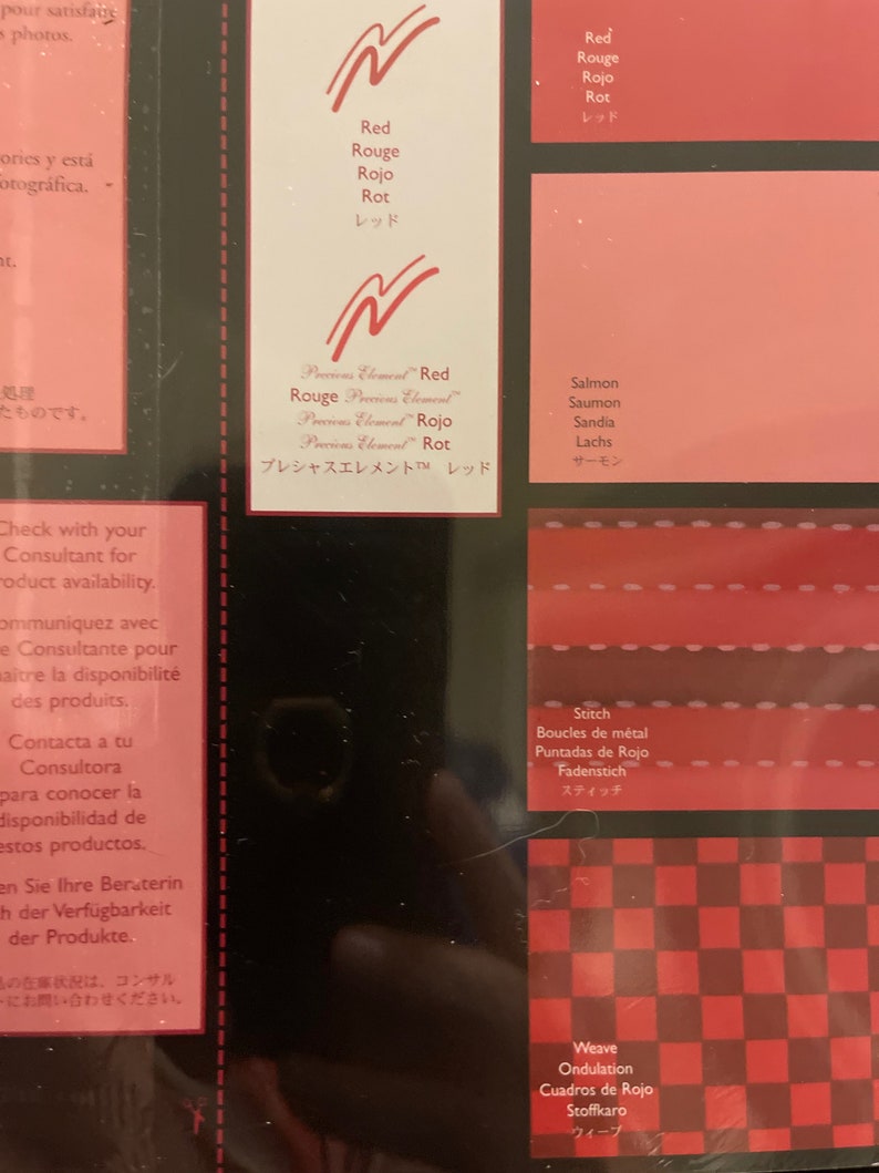 May include: A close-up of a color chart with different shades of red. The chart includes the words "Red", "Rouge", "Rojo", "Rot", and "レッド" in multiple languages. The chart also includes the words "Salmon", "Saumon", "Sandia", "Lachs", and "サーモン" in multiple languages. The chart also includes the words "Stitch", "Boucles de m&eacute;tal", "Puntadas de Rojo", "Fadenstich", and "スティッチ" in multiple languages. The chart also includes the words "Weave", "Ondulation", "Cuadros de Rojo", "Stoffkaro", and "ウィープ" in multiple languages.