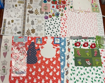 May include: Assortment of Christmas themed paper crafting supplies.  Includes patterned paper, stickers, and die cuts.  The paper features snowman, stocking, and candy cane designs.  The stickers feature Christmas trees, ornaments, and snowflakes.  The die cuts feature snowmen and snowflakes.