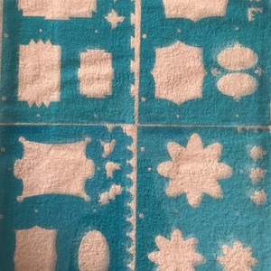 May include: A blue stencil sheet with various shapes and designs, including squares, circles, stars, and flowers. The stencil is made of a durable material and is perfect for crafting projects.