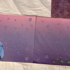 May include: A purple and pink gradient scrapbook paper with a Cinderella illustration on the left side and a pumpkin vine on the right side. The paper is decorated with small white stars and purple flowers.