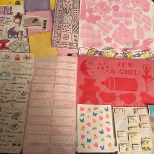 May include: A collection of pink and white baby girl scrapbook paper, stickers, and embellishments. The paper includes a variety of designs, including flowers, stars, and hearts. The stickers feature a variety of baby-related themes, such as baby animals, baby bottles, and baby carriages. The embellishments include ribbons, bows, and buttons.