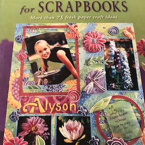 May include: A scrapbook page with a colorful floral design. The page features a photo of a young girl, a dragonfly, and the name "Alyson". The page also includes a quote from Ralph Waldo Emerson about the joy of playing.