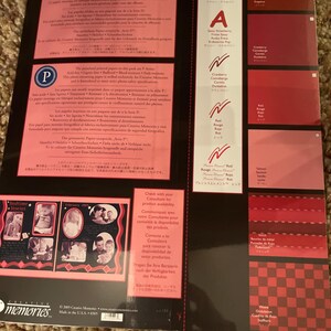May include: A Creative Memories scrapbook paper pack featuring various shades of red and pink. The pack includes color swatches, text, and sample photos. The paper is designed for scrapbooking and photo preservation.
