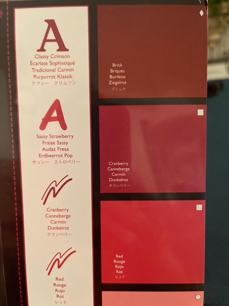 May include: A color palette featuring various shades of red, from deep brick to vibrant cranberry and classic red. Each color is labeled with its name in multiple languages, including English, French, Spanish, and Japanese.