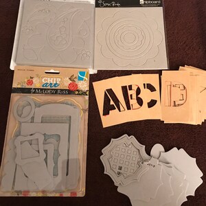 May include: A set of chipboard die cuts for crafting. The set includes a paisley design, a circle with concentric circles, a set of letters, a set of frames, and a set of decorative shapes.