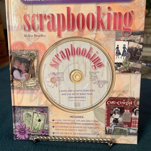May include: A scrapbooking kit by Helen Bradley, featuring a book and CD with templates and clip art. The cover displays the word "scrapbooking" in a pink, stylized font, with images of scrapbook pages and the text "Cute Cowgirl".