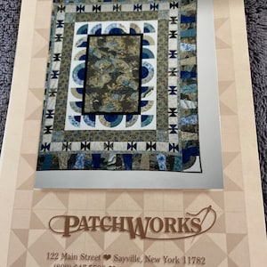 May include: A printed image of a quilt with a central rectangular design featuring a floral pattern. The quilt has a blue, white, and tan color scheme with a semi-circular pattern. The image is on a cream-colored background with the text "PATCHWORKS" and contact information.