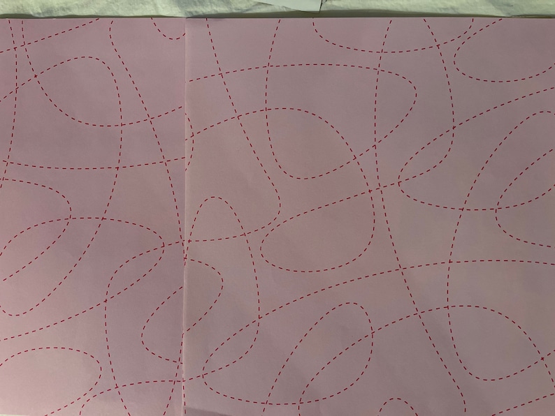 May include: A pink sheet of paper with a pattern of red dashed lines forming abstract shapes.