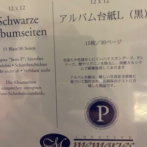 May include: A black photo album with the text "Schwarze bumseiten" and "Albumseiten entsprechen strengsten Foto-Sicherheitsstandards."  The album is 12 x 12 inches and holds 15 sheets or 30 pages.