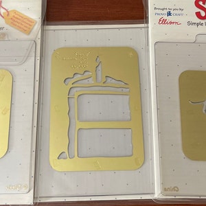 May include: Three Sizzix Simple Impressions embossing folders. One gold folder reads "You're Invited". Another gold folder has a cake design. The third gold folder reads "thanks". All are in clear plastic packaging.