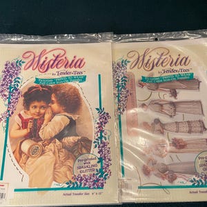 May include: Two sealed packages of Wisteria iron-on transfers. One features two children whispering, the other shows Victorian dresses. Both packages have the text "Victorian PRINTS TO WEAR" and "Pre-printed with SPARKLING GLITTER". The actual transfer size is 9" x 12".