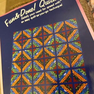 May include: A quilting pattern book titled "Fun & Done! Quilting" with the number 101. The cover features a grid of colorful, patterned squares in shades of blue, orange, green, and red. The text reads, "Satisfy your need for speed with an easy quilt-as-you-go technique!"