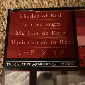 May include: A red-toned product box with the text "Shades of Red" in English, French, Spanish, German, and Japanese. The Creative Memories Collection logo is visible.