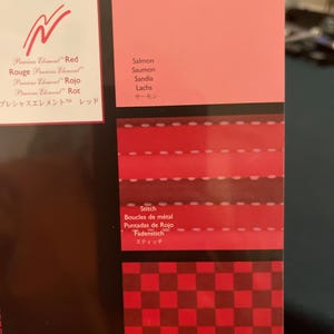 May include: A color chart featuring various shades of red, including salmon. The chart displays different textures and patterns, such as stitching and a checkered weave, with corresponding color names in multiple languages.