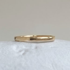 May include: A simple gold band ring with a smooth, slightly rounded surface.