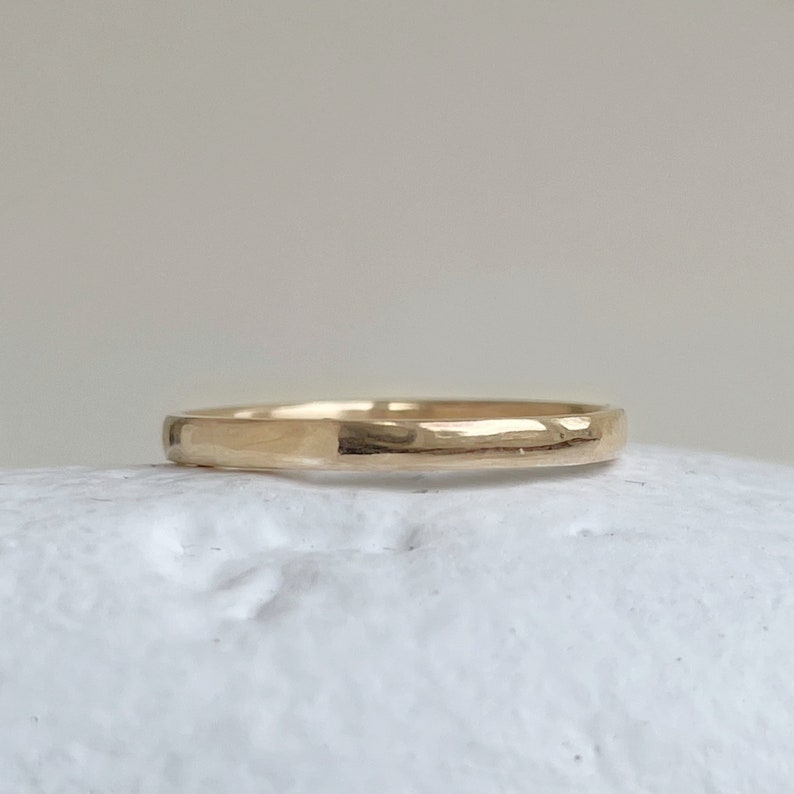 May include: A simple gold band ring with a smooth, slightly rounded surface.