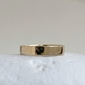May include: A simple gold band ring with a smooth, polished finish.