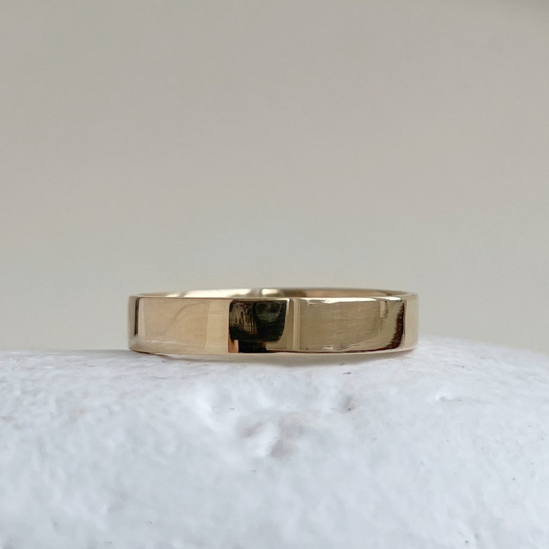 May include: A simple gold band ring with a smooth, polished finish.