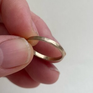 May include: A simple gold band ring with a hammered finish.