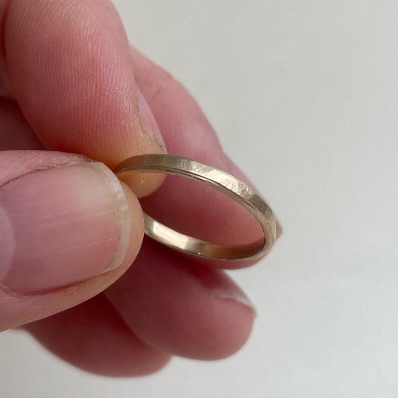 May include: A simple gold band ring with a hammered finish.
