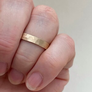 May include: A simple gold band ring with a hammered texture.