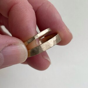 May include: Two gold hammered wedding bands stacked on top of each other.