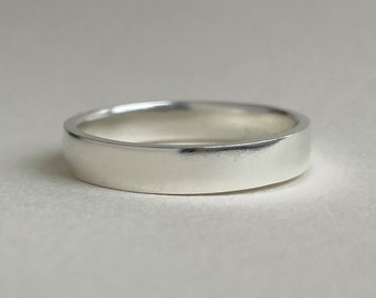 May include: A simple silver band ring with a smooth, polished finish.