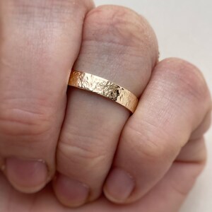 May include: A gold band ring with a hammered texture.
